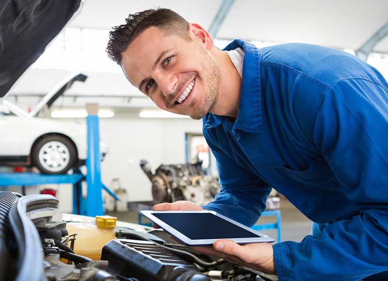 Mechanic inspecting a car engine with a tablet